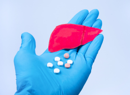 Gloved hand holding pills and a liver representing substance abuse and Hepatitis C